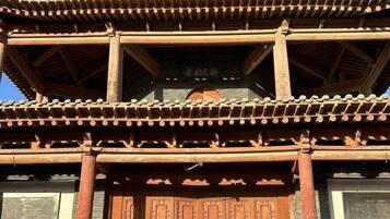 Una estructura de madera tradicional con varios niveles, techo de tejas y una puerta grande de madera.
