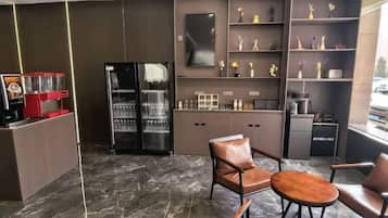Une cuisine moderne avec un revêtement de sol en marbre, des appareils électroménagers intégrés et un coin salon doté de fauteuils en cuir et d’une petite table.