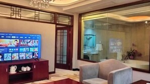 A living room with a TV, a sofa, a coffee table, and a decorative cabinet. - Zhangye Jiaheng International Hotel (Municipal Government & Big Buddha Temple Branch) (Zhangye)