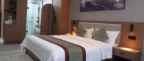 A hotel room with a large bed, a nightstand, a wall-mounted TV, and a bathroom visible through an open door.