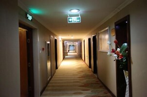 Un pasillo de hotel con suelo alfombrado y puertas a ambos lados, con un cartel sobre ellas.