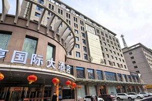 A hotel with a curved facade, multiple floors, and a prominent entrance with a sign.