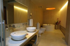 Een moderne badkamer met een grote spiegel, twee wasbakken, een toilet en een bad.
