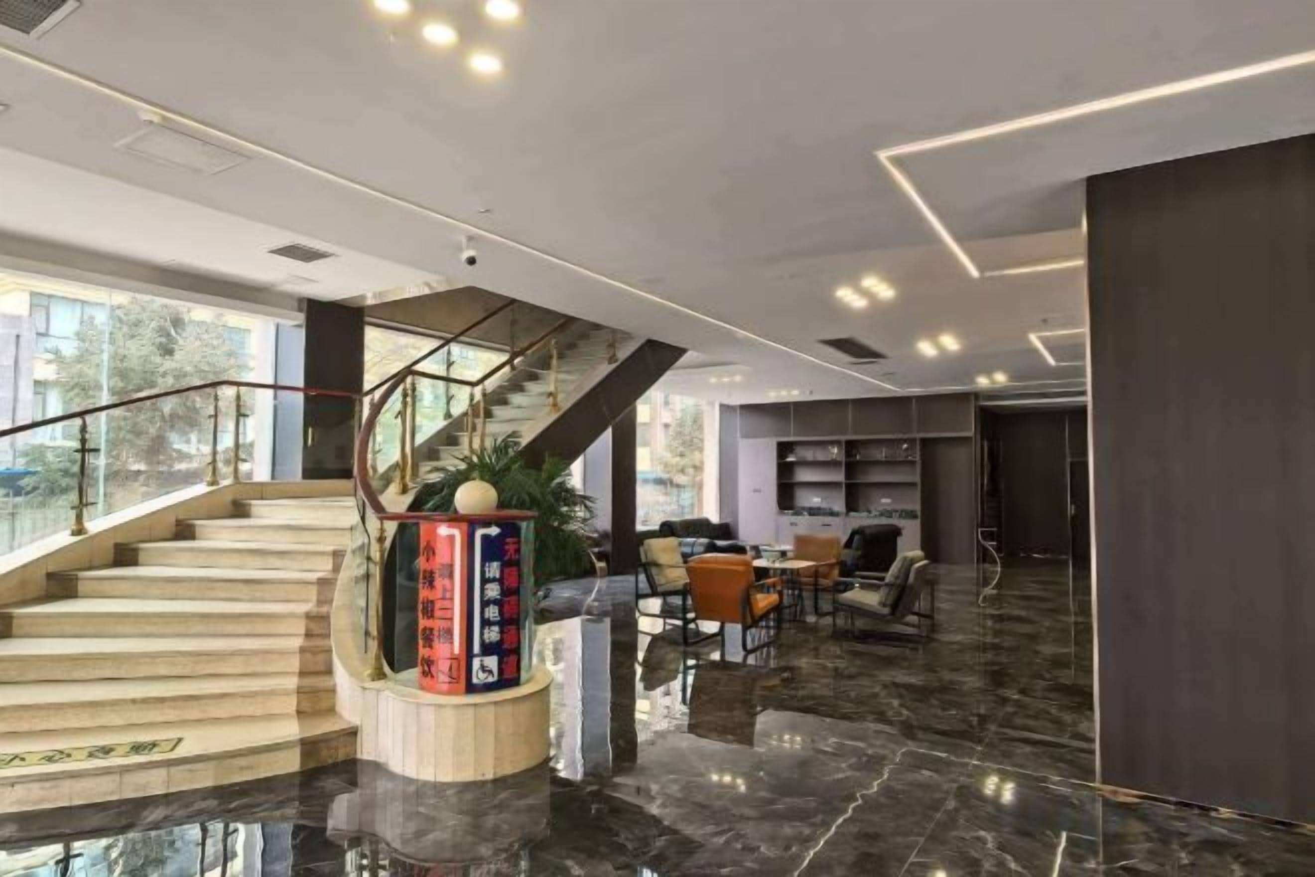 A hotel lobby with a marble floor, a staircase, a reception desk, and a seating area.