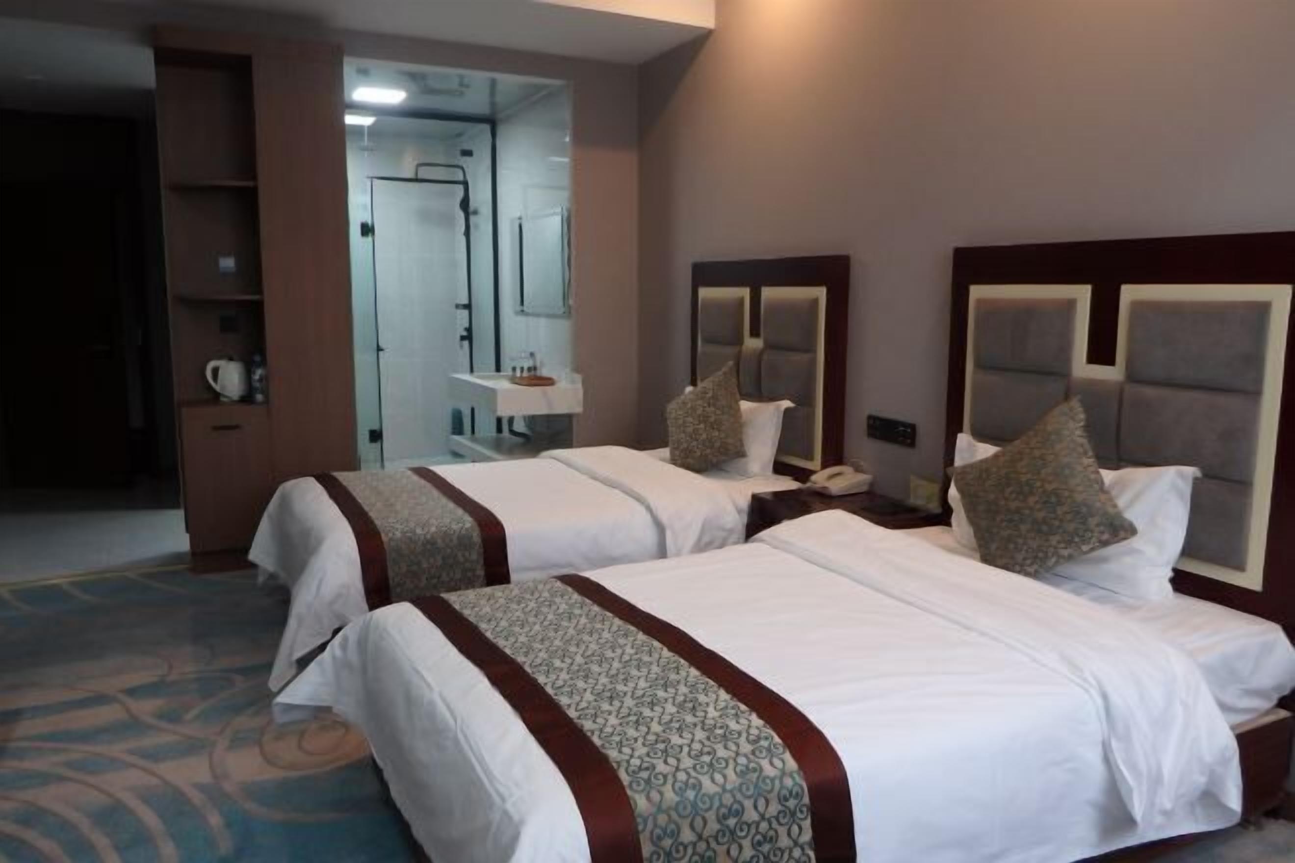 Habitación de hotel con dos camas, baño y zona de ducha.