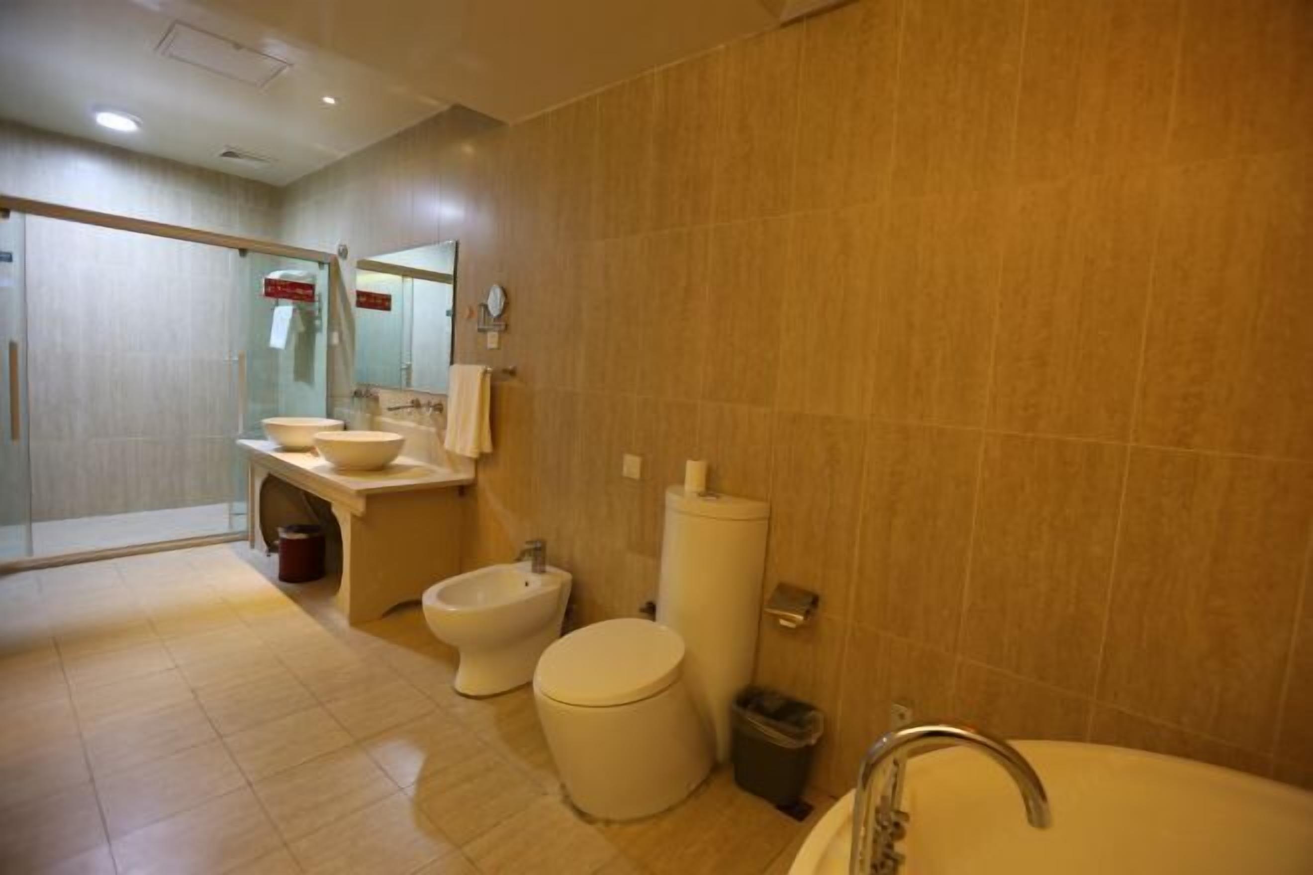 A modern bathroom with a toilet, bidet, sink, and a large bathtub.