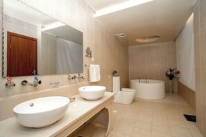 Een moderne badkamer met twee grote wastafels, een bad en een toilet.