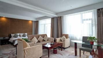 Quarto de hotel moderno com sofá, mesa de jantar e cama.