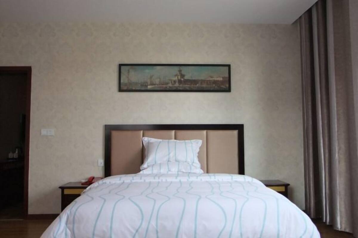 Ein Hotelzimmer mit Bett, Nachttisch, einem Bild an der Wand und einer Tür.