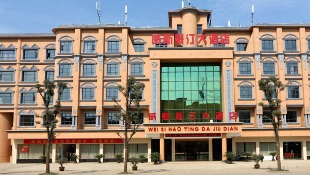 Un hotel de varios pisos con fachada central de vidrio y numerosas ventanas.
