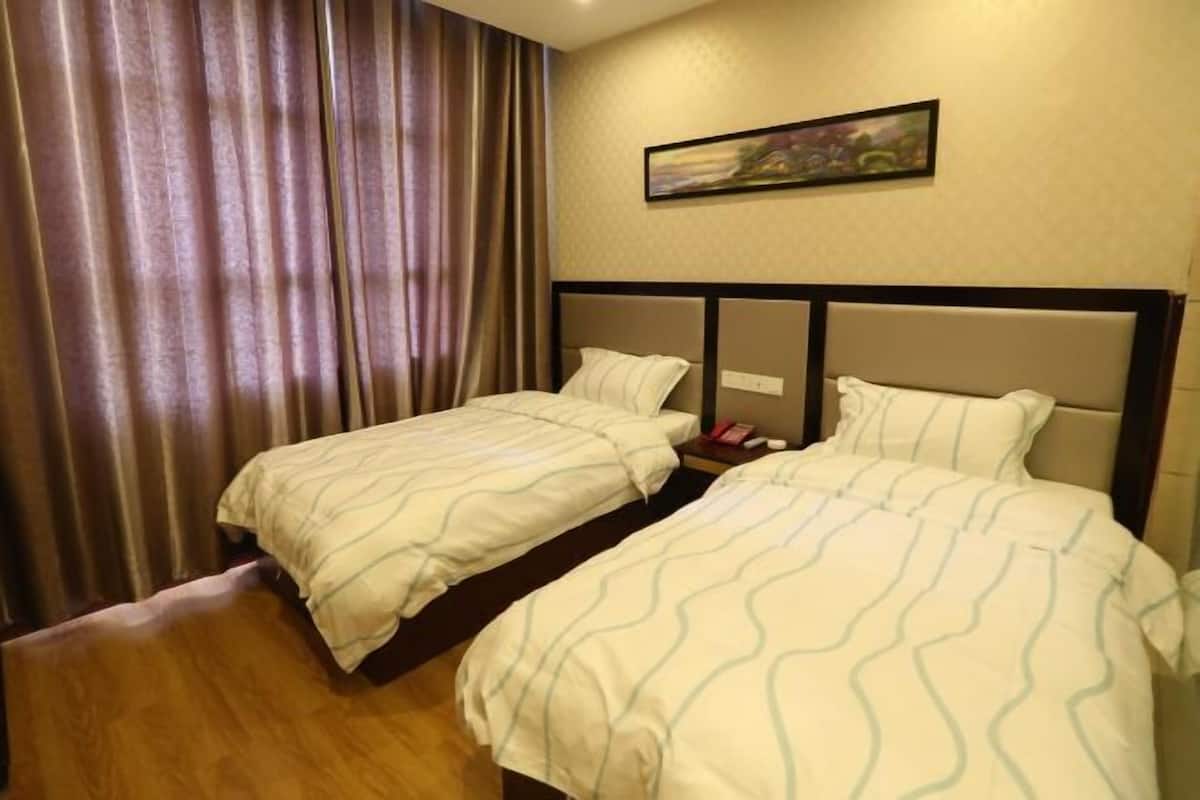 Ein Hotelzimmer mit zwei Betten, einem Bild an der Wand und einem Vorhang.