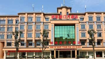 A multi-story hotel with a central glass facade and signage indicating 'WEI SI HAO TING DA DIAN'.