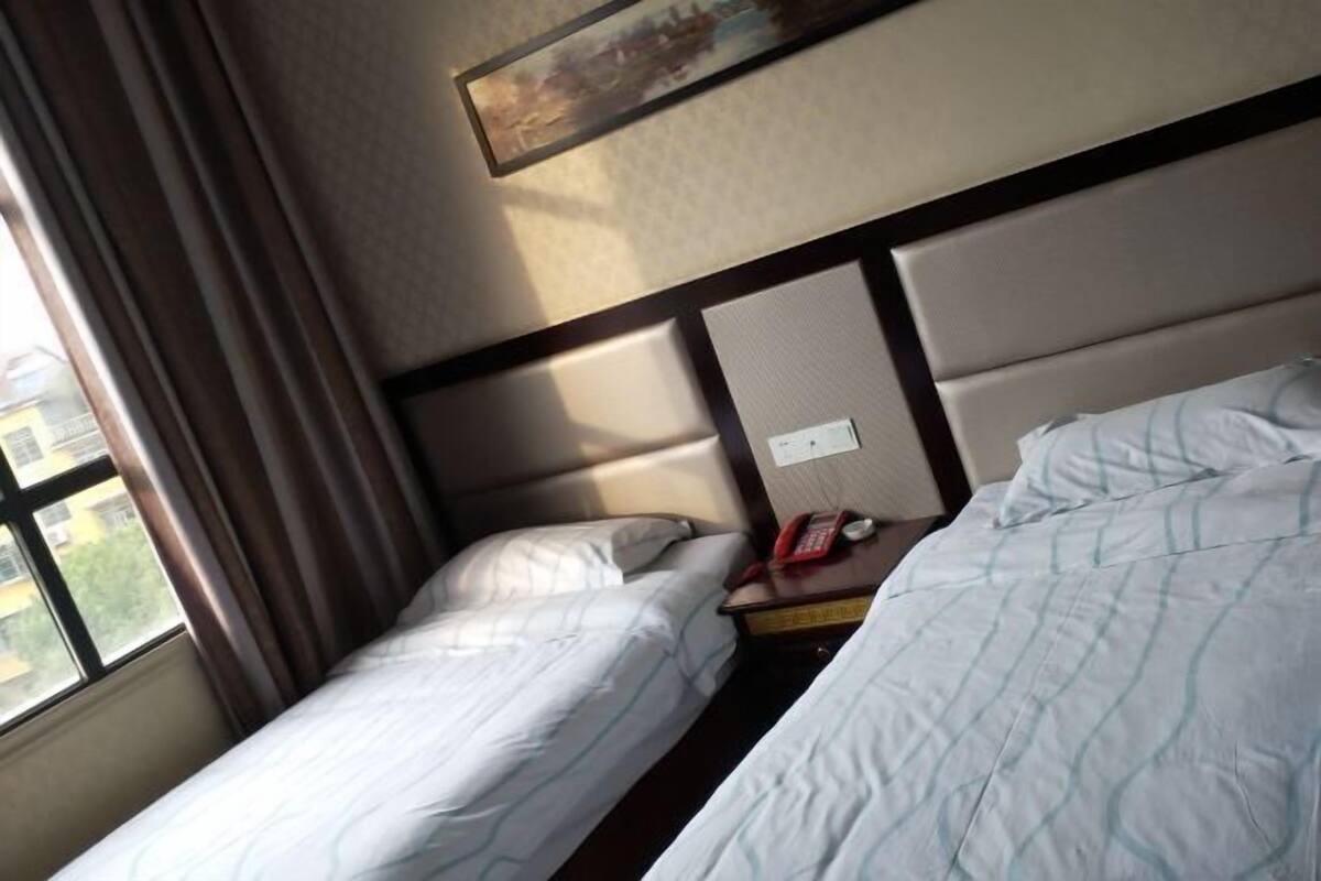 Ein Hotelzimmer mit zwei Betten, einem Nachttisch mit Telefon und einem Bild an der Wand.