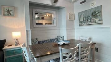 A dining area with a wooden table, white chairs, and a bench with patterned cushions.