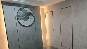 Ein modernes Zimmer mit Marmorwand, einem runden Kunstwerk und einer Tür.