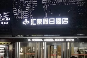 A hotel entrance with a large illuminated sign displaying the name and contact information. - Huiquan Holiday Hotel (Guiyang)