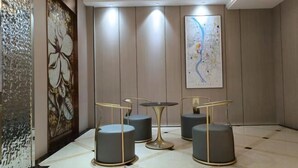 Eine moderne Lobby mit einer Karte an der Wand, einer Zierwandverkleidung und einer Sitzecke mit rundem Tisch und Stühlen.