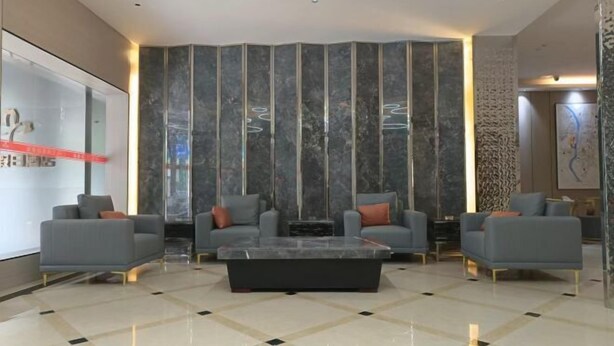 Eine moderne Lobby mit Marmorboden, grauen Sofas und einem zentralen Couchtisch.