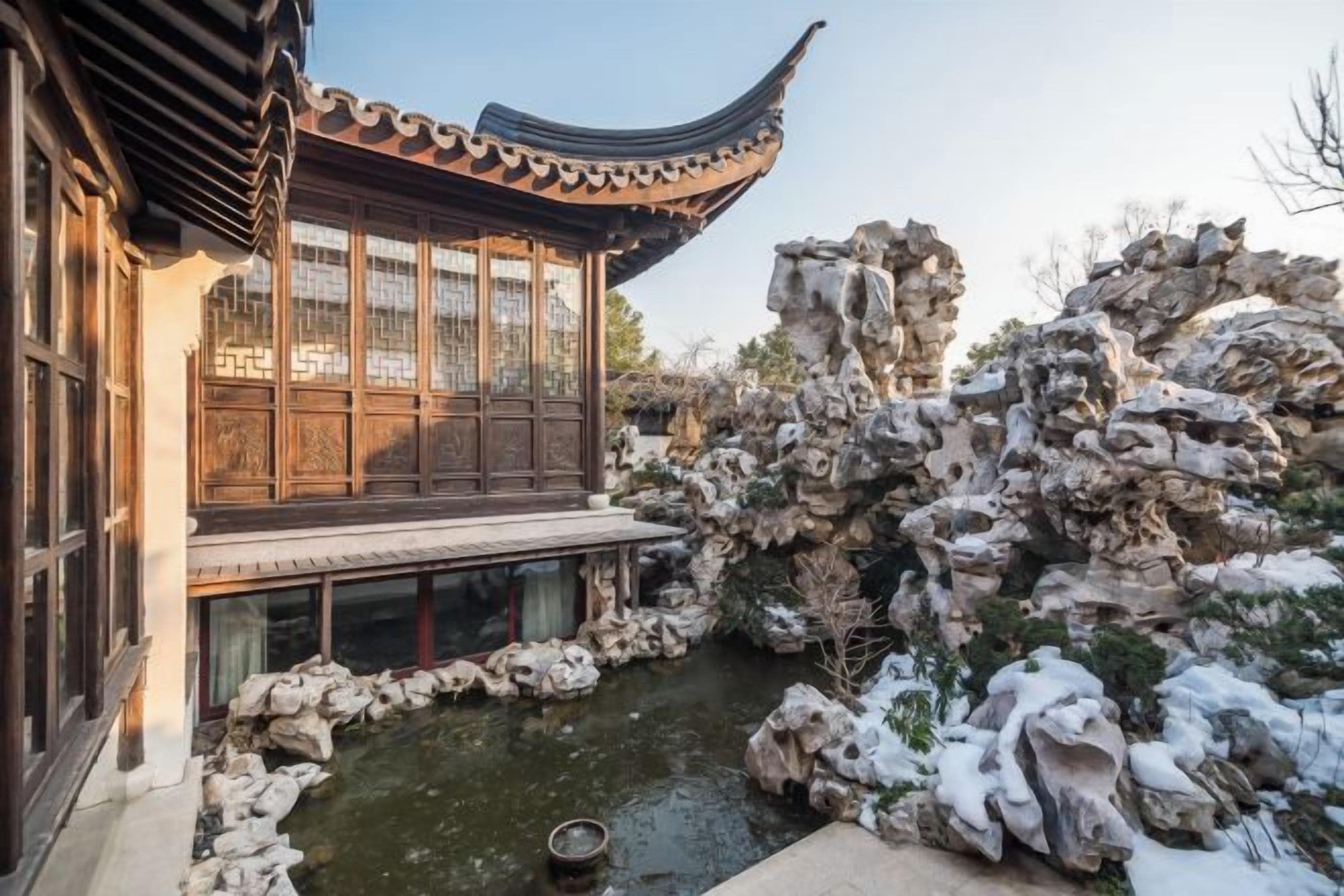 A traditional building with a curved roof and a pond in the courtyard.
