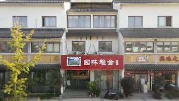 A traditional building with a signboard, a tiled entrance, and a small garden area.
