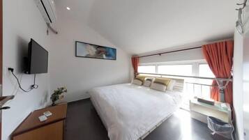 A hotel room with a bed, a desk, a TV, a window with curtains, and a painting on the wall.