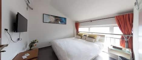 A hotel room with a bed, a desk, a TV, a window with curtains, and a painting on the wall.