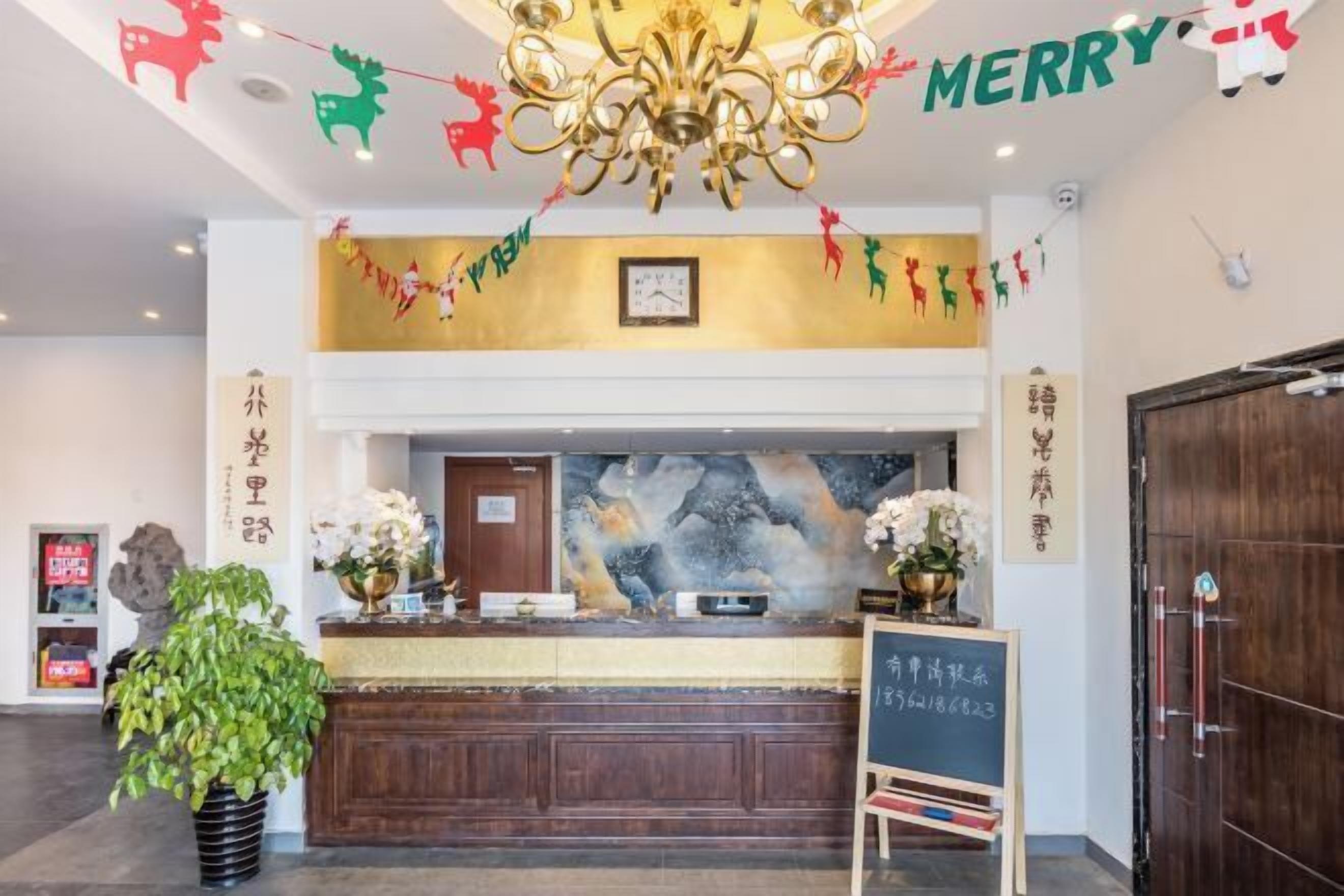 A hotel reception area with a chandelier, a clock, and festive decorations.