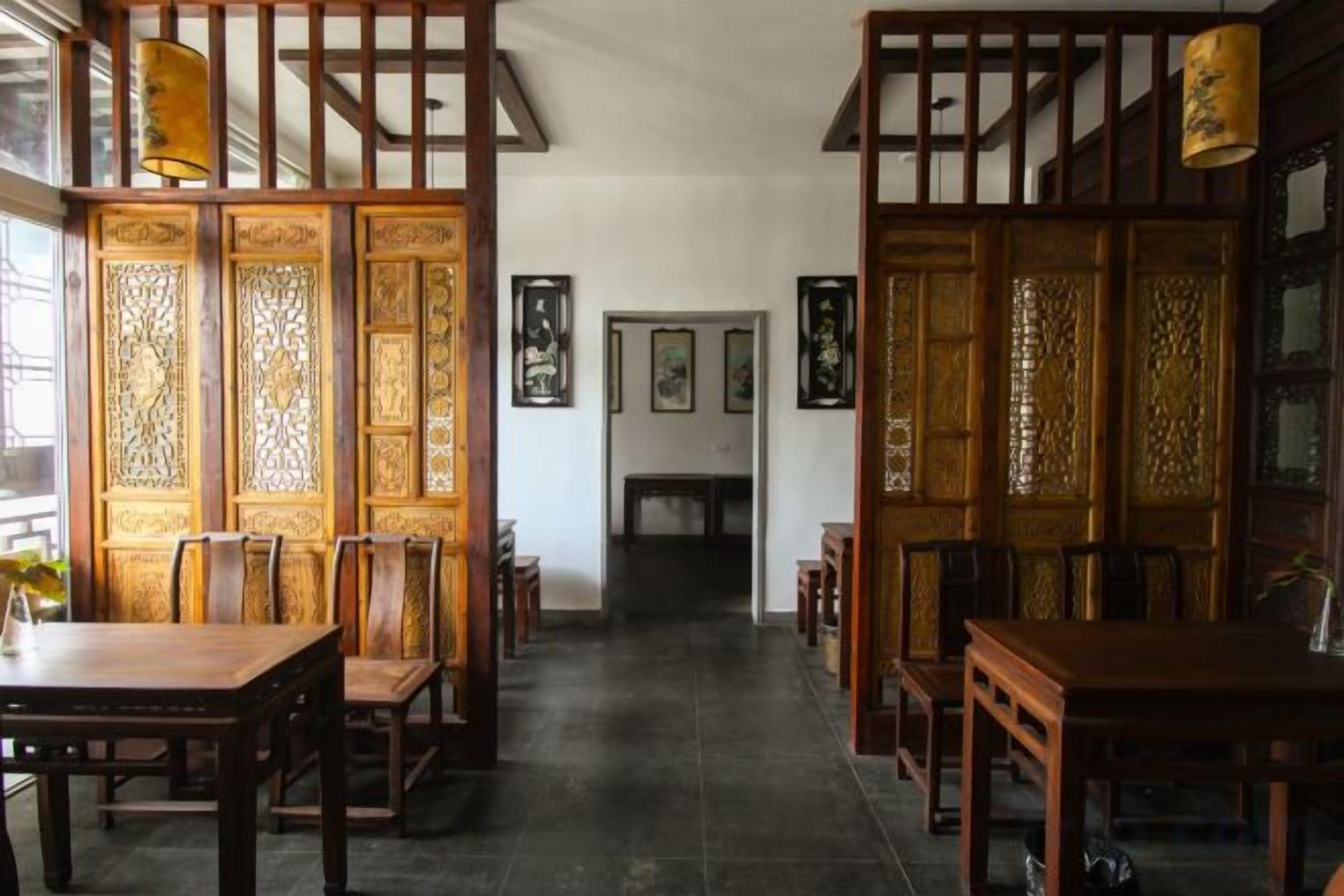 A traditional interior with a wooden partition, a dining table, chairs, and a view through the partition.