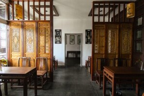 A traditional interior with a wooden partition, a dining table, chairs, and a view through the partition.