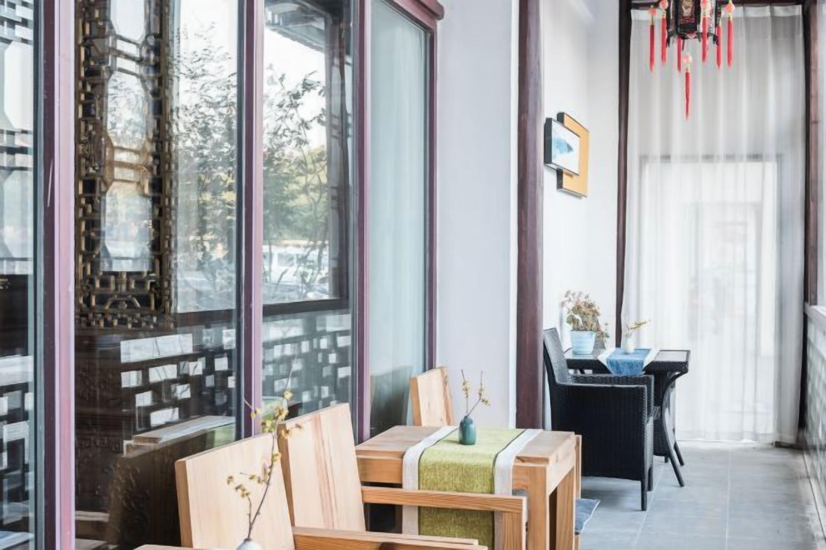 A room with a wooden table, chairs, and a view through large windows.