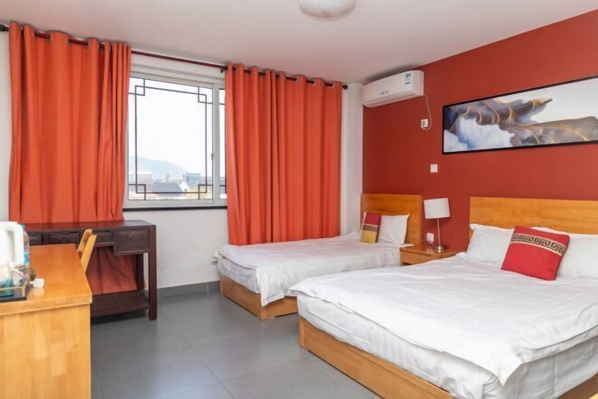 A hotel room with two beds, a desk, and a window with curtains.