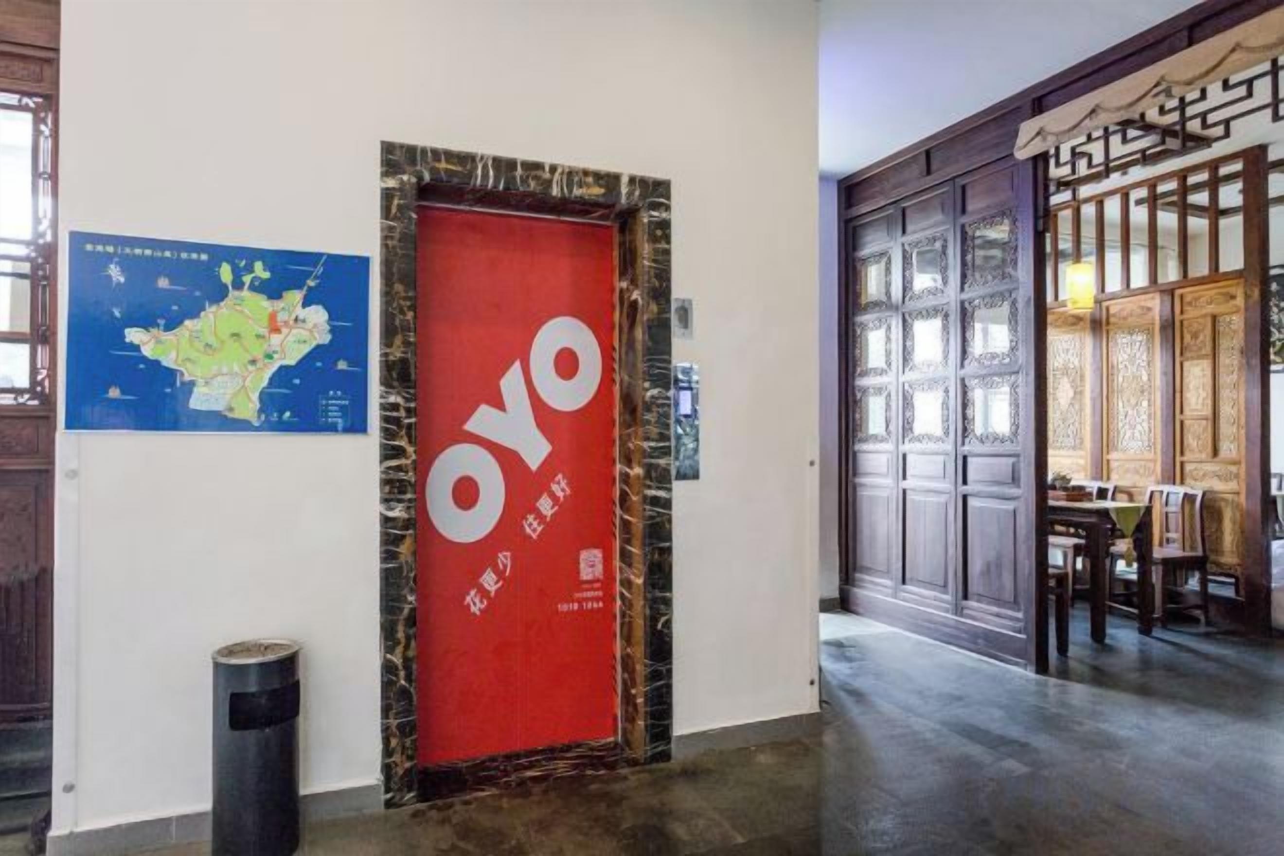 Un pasillo con una puerta roja identificada con 'OYO' y un mapa en la pared.