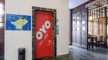 Un pasillo con una puerta roja identificada con 'OYO' y un mapa en la pared.