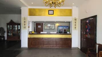 A reception desk with a clock above it, a wooden cabinet to the left, and a door with a colorful design to the right.