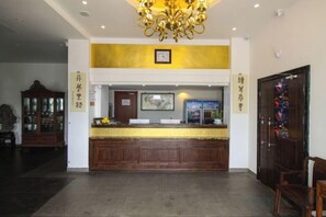 A reception desk with a clock above it, a wooden cabinet to the left, and a door with a colorful design to the right. - Yuanlin Hotel (Suzhou)