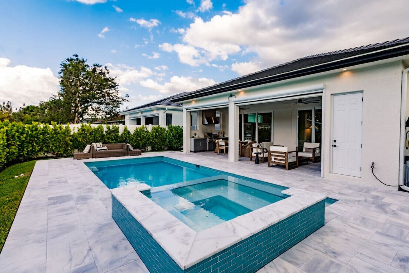 A modern house with a swimming pool, outdoor seating, and a covered patio area.