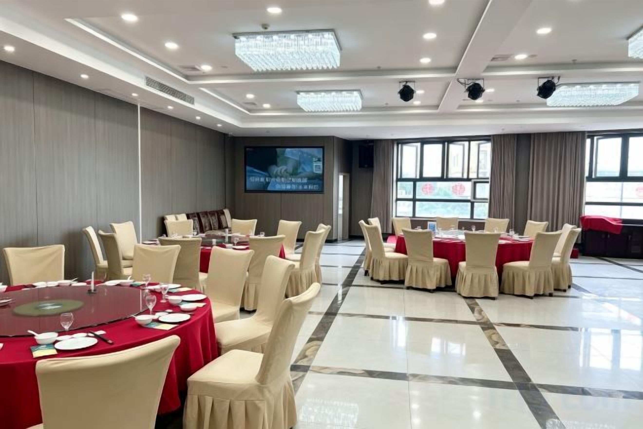 Un salón de conferencias con mesas redondas, sillas, una pantalla grande y vista al mar.