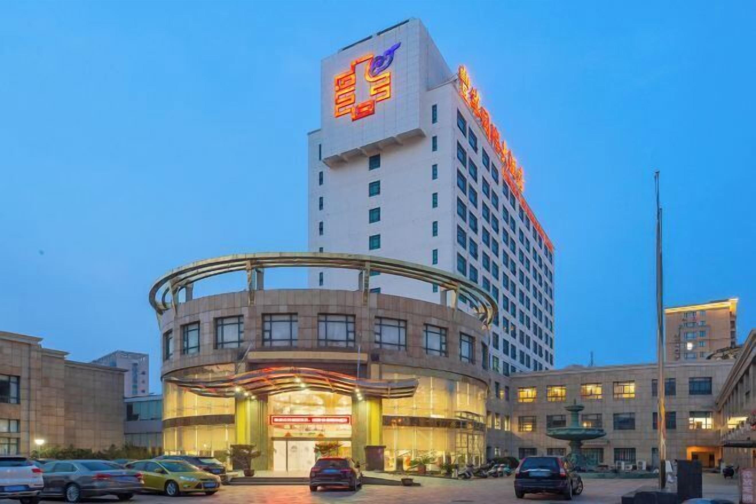 A hotel with a prominent sign on the top, a curved entrance, and multiple floors.