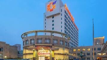 A hotel with a prominent sign on the top, a curved entrance, and multiple floors.