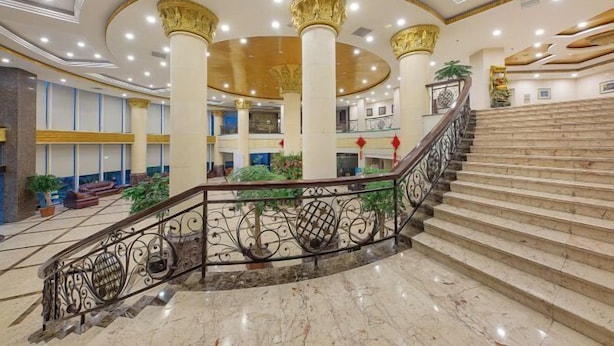 A grand lobby with a marble staircase, ornate columns, and a spacious atrium.