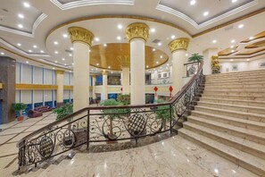 Un vestíbulo amplio con un atrio central, una escalera y una barandilla decorativa.
