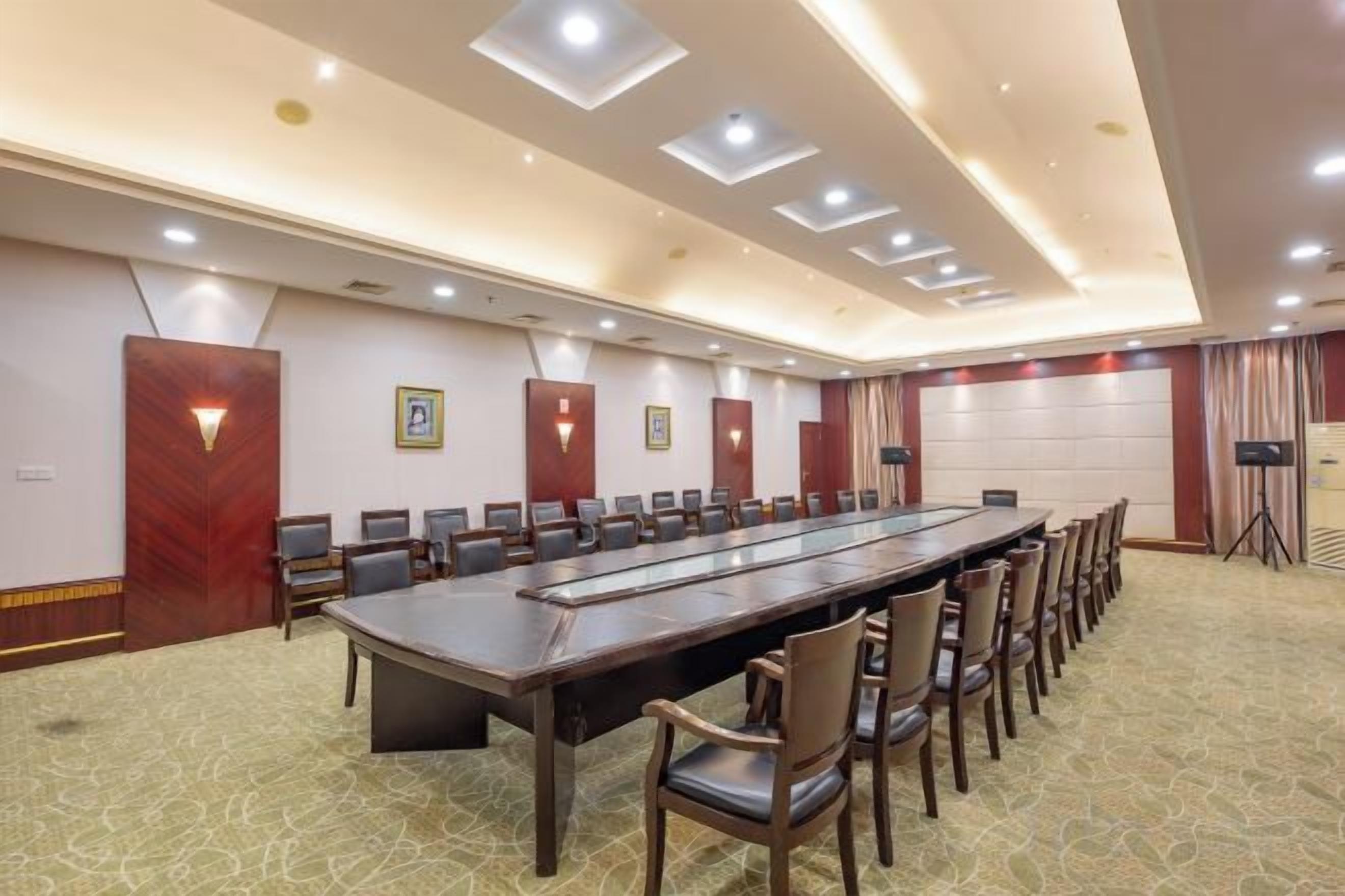 A conference room with a long table and chairs, recessed lighting, and a patterned carpet.