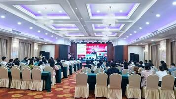 A conference room with rows of chairs facing a stage with a presentation screen.