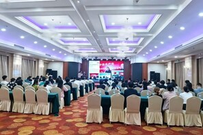 A conference room with rows of chairs facing a stage with a presentation screen. - Fenghua International Hotel (Shengsi)