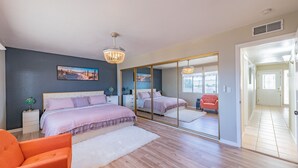 Ein Schlafzimmer mit einem großen Bett, einem Spiegel, einer Kandelaber und Blick ins Freie.