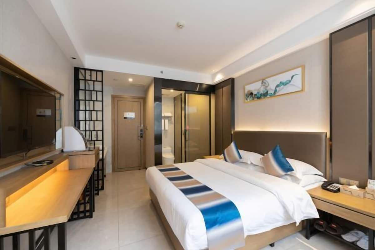 Une chambre d’hôtel avec un lit, une table de chevet, un bureau et un grand miroir.