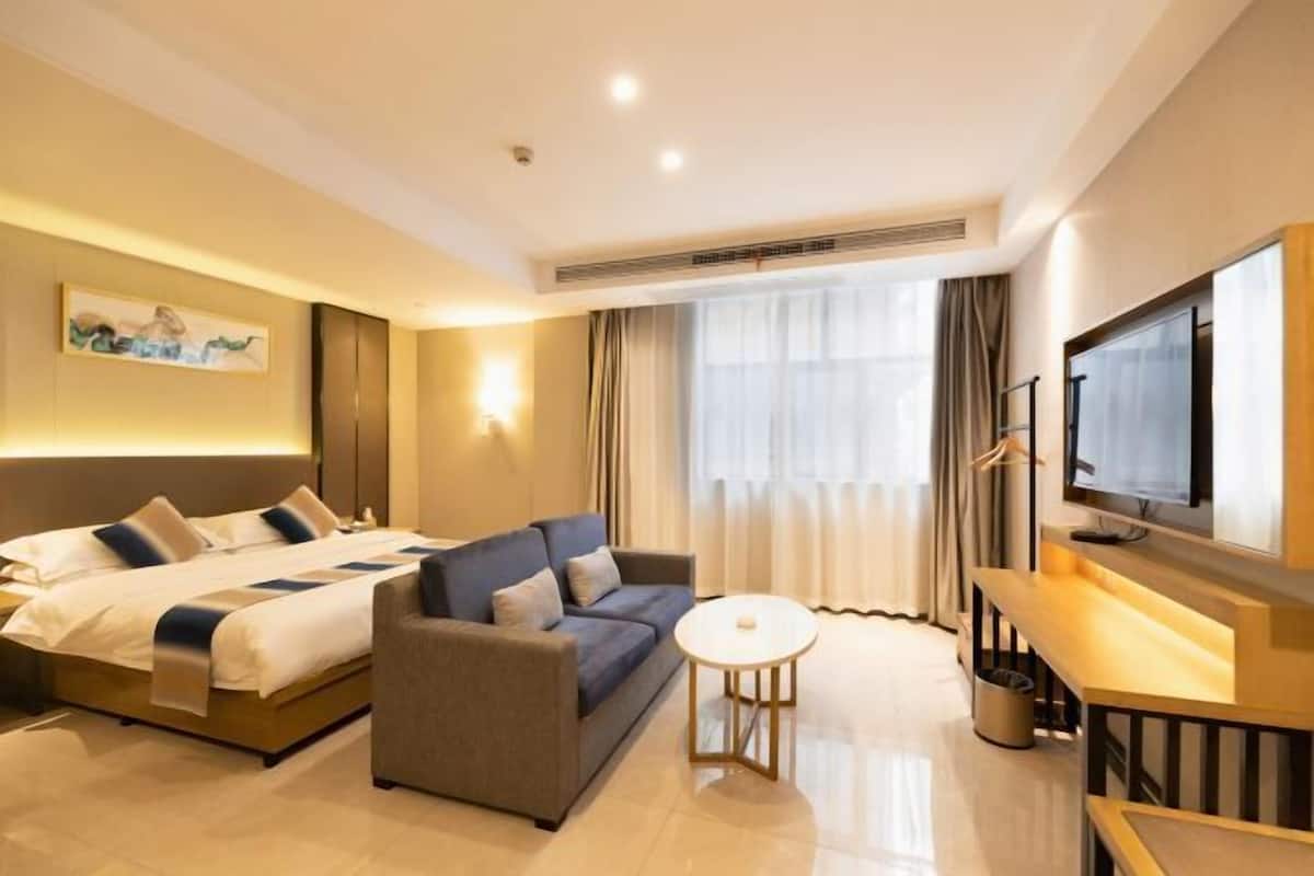 Une chambre d’hôtel avec un lit, un canapé, une télévision et une petite table.