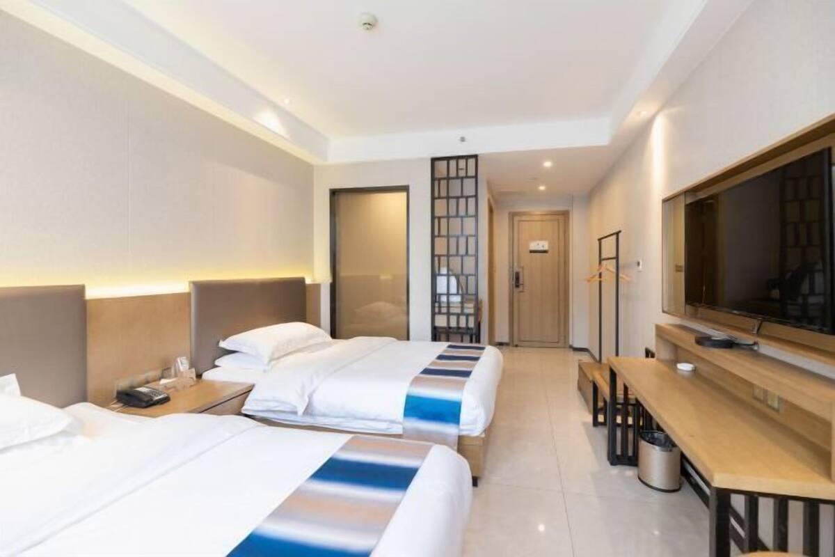 Une chambre d’hôtel avec deux lits, une télévision, un bureau et un coin salon.