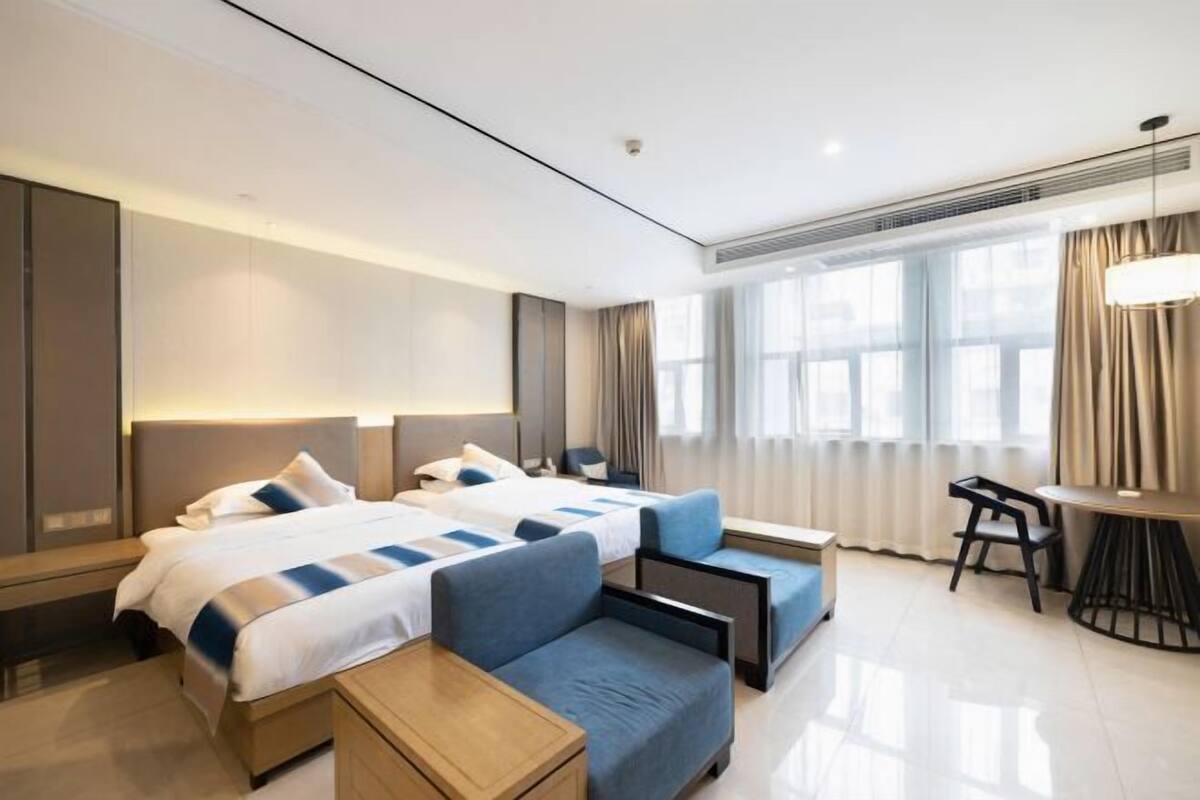 Une chambre d’hôtel moderne avec deux lits, un bureau et une chaise.