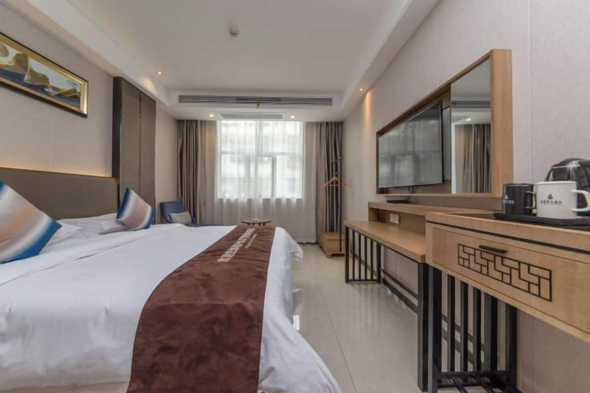 Une chambre d’hôtel avec un lit, un bureau, un miroir et une télévision.
